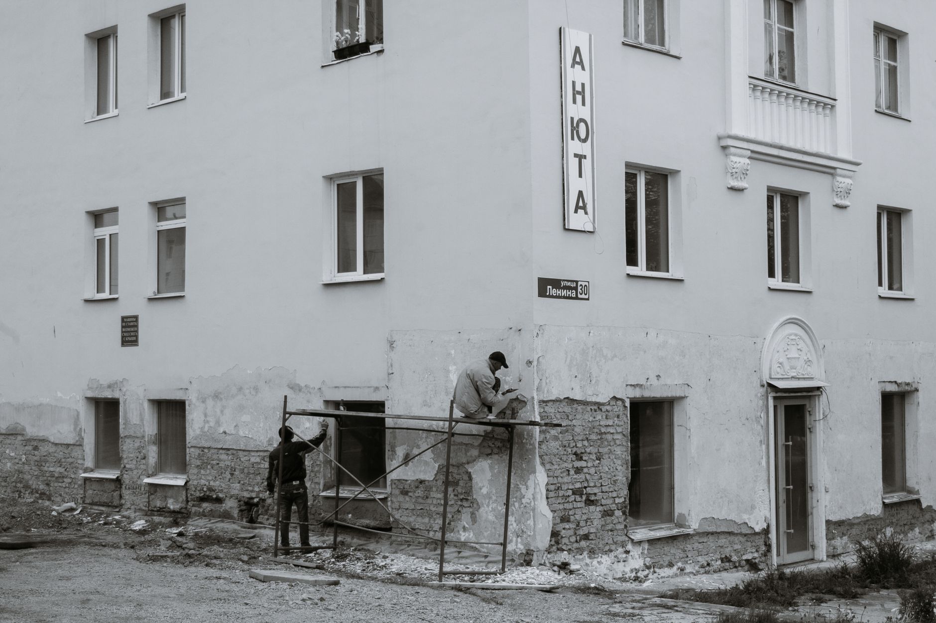 Zwei Handwerker sanieren die Wand eines Wohnhauses