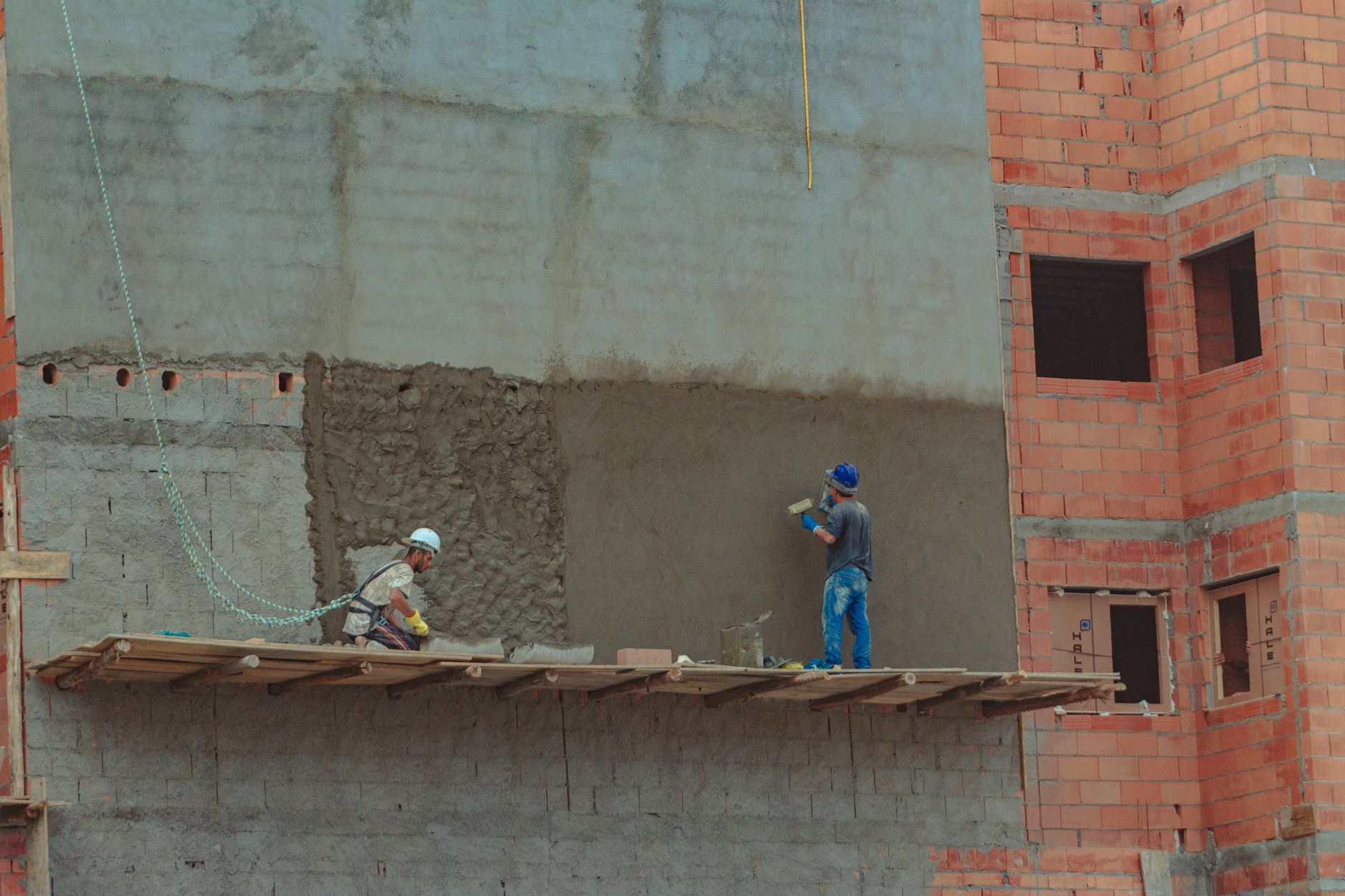 Handwerker auf einer Baustelle vor einer Ziegelfassade